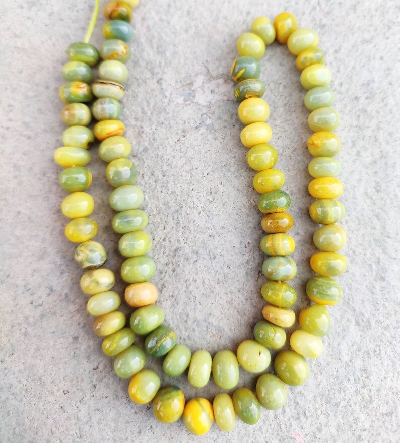 May include: A strand of green and yellow gemstone beads. The beads are round and have a smooth, polished finish.