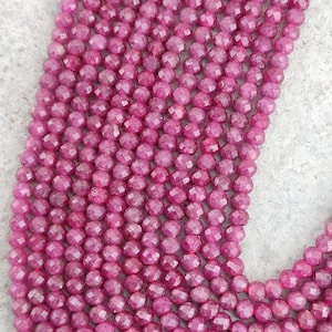 Può includere: Una collana di perline di pietra preziosa rosa sfaccettate. Le perline sono rotonde e hanno una finitura liscia e lucida.