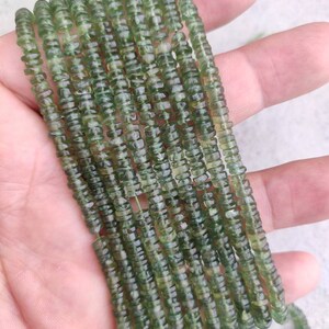 May include: A strand of green gemstone beads, each bead is faceted and has a slightly irregular shape. The beads are strung on a clear thread and are approximately 4mm in diameter.