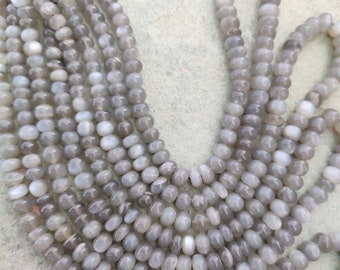 May include: A strand of gray moonstone beads. The beads are round and have a smooth, polished finish. The beads are strung on a clear thread.