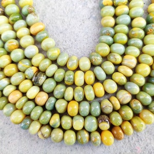 May include: A strand of green and yellow gemstone beads. The beads are smooth and round, and they have a natural, organic look.