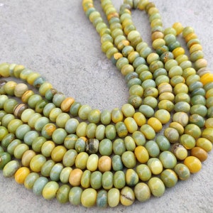May include: A strand of green and yellow gemstone beads. The beads are round and have a smooth, polished finish.