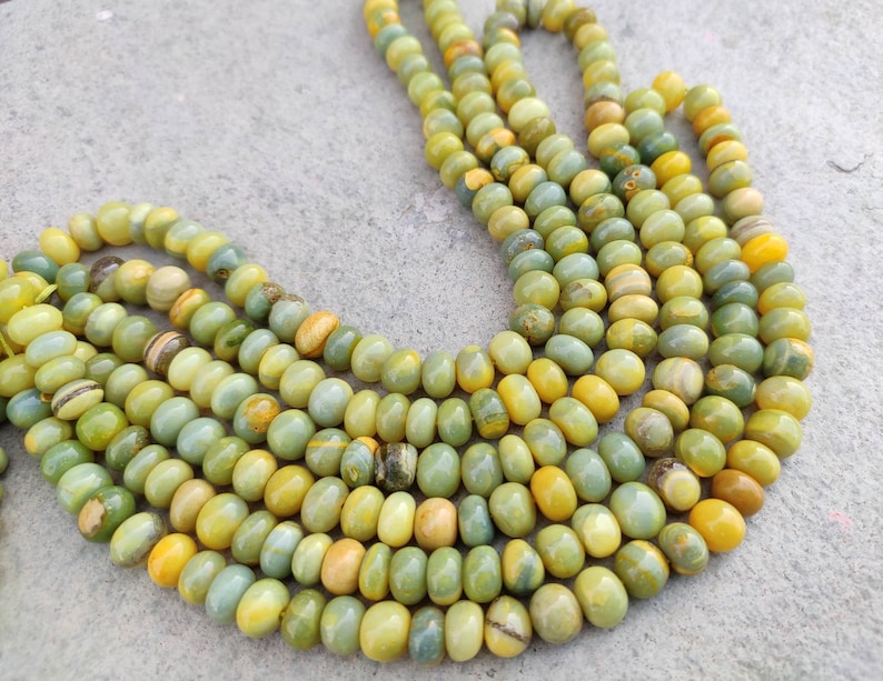 May include: A strand of green and yellow gemstone beads. The beads are round and have a smooth, polished finish.