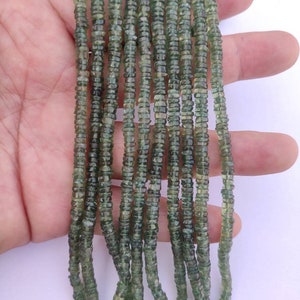 May include: A strand of green gemstone beads, with a faceted, slightly irregular shape. The beads are strung on a clear thread and are approximately 4mm in diameter.