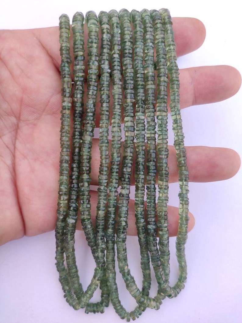 May include: A strand of green gemstone beads, with a faceted, slightly irregular shape. The beads are strung on a clear thread and are approximately 4mm in diameter.