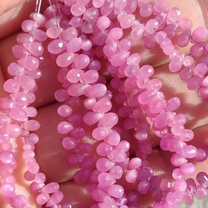 Puede incluir: Una hebra de cuentas de piedras preciosas rosas, cada cuenta está facetada y tiene forma de lágrima. Las cuentas están enhebradas en un alambre fino y están listas para ser utilizadas en la elaboración de joyas.
