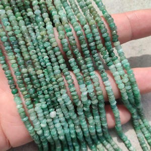 Peut inclure: Plusieurs brins de petites perles rondes vert émeraude. Les perles sont enfilées ensemble, créant plusieurs lignes de la même pierre précieuse. Les perles ont une forme légèrement irrégulière et une finition polie.