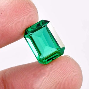 Puede incluir: Una gema de esmeralda verde vibrante tallada en forma de esmeralda.