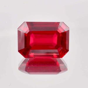 Puede incluir: Una piedra preciosa de color rojo intenso tallada en esmeralda con un alto pulido.