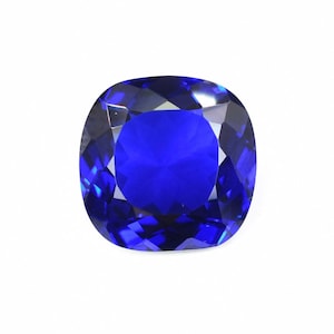 May include: A faceted, cushion-cut gemstone in a vibrant, deep blue hue. The gem's facets reflect light, creating a brilliant sparkle. The shape is a rounded square, perfect for jewelry.