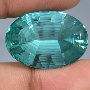 May include: A large, oval-shaped, faceted gemstone with a light blue-green color. The gemstone has a high degree of clarity and brilliance.