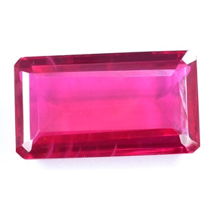 May include: A vibrant pink gemstone with a rectangular cut and a smooth, polished finish.