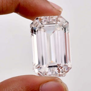 May include: A large, clear, emerald-cut gemstone with many facets.