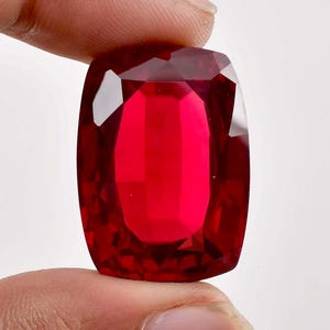 May include: A large, deep red, faceted gemstone with a rectangular shape.