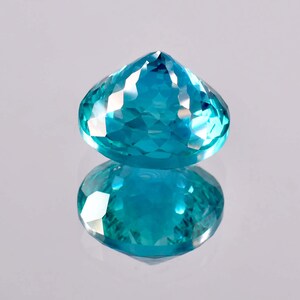 May include: A vibrant blue gemstone with a faceted cut, reflecting light in a dazzling display. The gemstone is oval-shaped and has a pointed top.