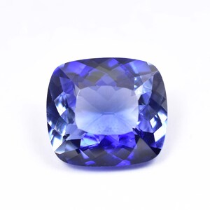May include: A deep blue gemstone with a cushion cut. The gemstone is faceted and has a high polish.