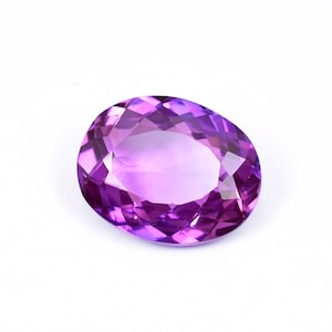 May include: A large, oval-shaped amethyst gemstone with a deep purple hue. The gemstone is faceted and has a high degree of brilliance.