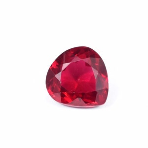 Puede incluir: Una piedra preciosa roja oscura en forma de corazón con un corte facetado.