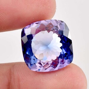 Puede incluir: Una gran gema de talla cojín con un degradado de tonos púrpura a azul. La gema está facetada y tiene un alto grado de brillo.