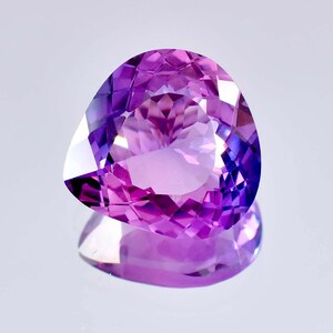 Puede incluir: Una gran gema de amatista púrpura facetada con forma de lágrima. La gema está tallada y pulida para un alto brillo.