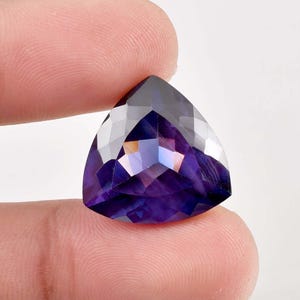 Peut inclure: Une pierre précieuse d'améthyste taillée en triangle avec un dégradé de couleur violet et clair. La pierre précieuse est facetée et a un brillant élevé.