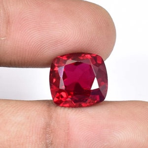 Peut inclure: Une pierre précieuse rouge foncé de forme coussin avec une surface facetée.