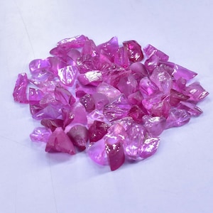 May include: A pile of pink ruby rough gemstones. The rough gemstones are various shapes and sizes.