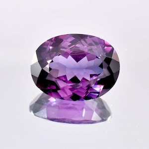 以下が含まれることがあります： 深い紫色の大きな楕円形の紫水晶の宝石。宝石はファセットカットされており、非常に輝いています。