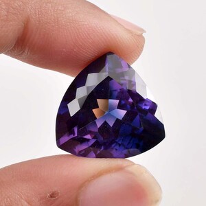 Puede incluir: Una gran piedra preciosa de amatista púrpura facetada con forma triangular.