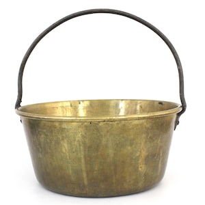 Peut inclure: Une casserole en cuivre avec une poignée en métal noir. La casserole est ronde et a une surface lisse.