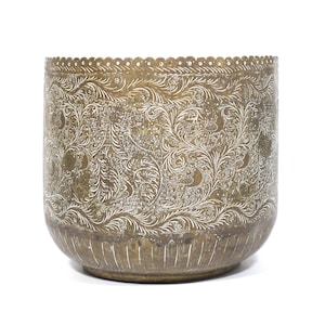 May include: A cylindrical brass planter featuring an intricate etched white floral and leaf pattern across its exterior surface. The top rim has a scalloped edge with small perforations, while the base displays vertical etched line details.