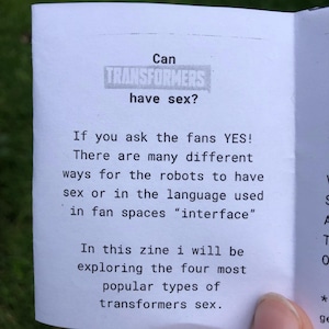 Pu&ograve; includere: Una pagina di fanzine in carta bianca con testo nero che recita: Can TRANSFORMERS have sex? If you ask the fans YES! There are many different ways for the robots to have sex or in the language used in fan spaces "interface" In this zine i will be exploring the four most popular types of transformers sex.