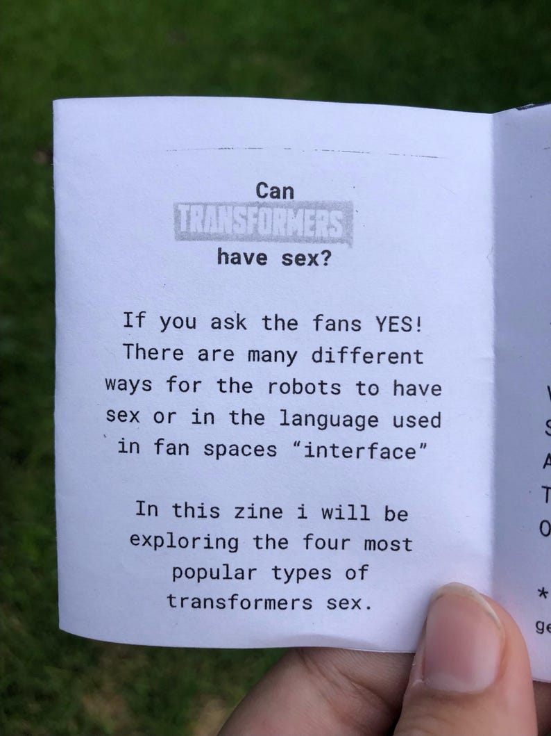 Pu&ograve; includere: Una pagina di fanzine in carta bianca con testo nero che recita: Can TRANSFORMERS have sex? If you ask the fans YES! There are many different ways for the robots to have sex or in the language used in fan spaces "interface" In this zine i will be exploring the four most popular types of transformers sex.