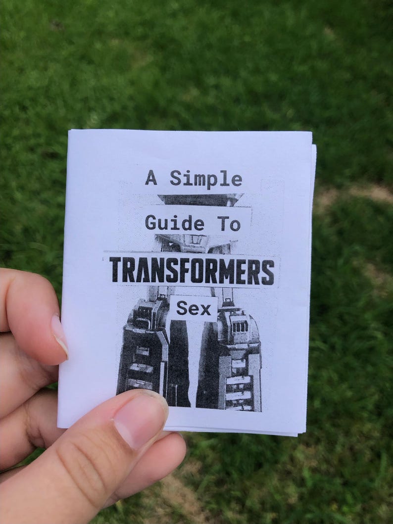Pu&ograve; includere: Un piccolo libretto bianco con una copertina stampata in bianco e nero che presenta un'illustrazione di un robot meccanico e il testo A Simple Guide To TRANSFORMERS Sex. Il libretto &egrave; realizzato in carta piegata con un'estetica pulita.