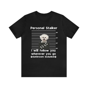 May include: A black t-shirt with a white graphic of a small white dog in a mugshot. The text "Personal Stalker" is above the dog and "I will follow you wherever you go bathroom included" is below the dog.