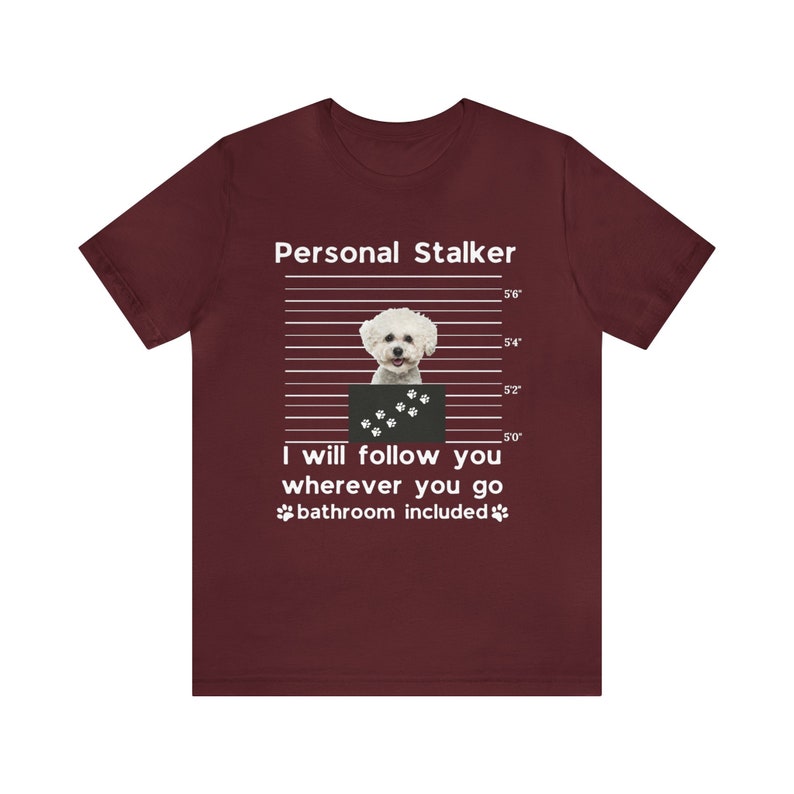 May include: A maroon t-shirt with a white graphic of a small white dog in a mugshot. The text "Personal Stalker" is above the dog and "I will follow you wherever you go bathroom included" is below the dog.