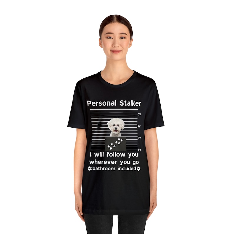 May include: Black t-shirt with a white graphic of a small white dog in a mugshot style with the text "Personal Stalker" and "I will follow you wherever you go bathroom included".