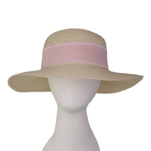 Pu&ograve; includere: Un cappello di paglia a tesa larga con un nastro rosa attorno alla corona.