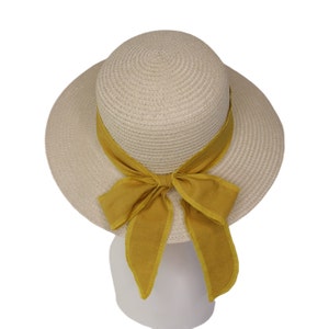 Pu&ograve; includere: Un cappello di paglia beige con un'ampia tesa e un fiocco di stoffa giallo.