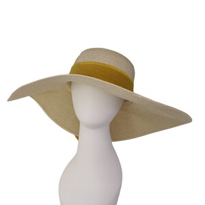 Pu&ograve; includere: Un cappello di paglia a tesa larga con un nastro giallo. Il cappello &egrave; beige e ha una tesa larga e morbida.