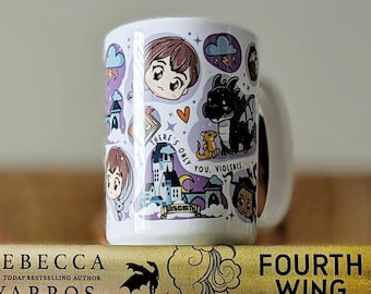 Pode incluir: Uma caneca de cerâmica branca com ilustrações de desenhos animados está em cima de dois livros e uma manta. Os livros são intitulados "Rebecca Yarros" e "Fourth Wing". A manta apresenta personagens de desenhos animados, castelos e o texto "Basgiath".