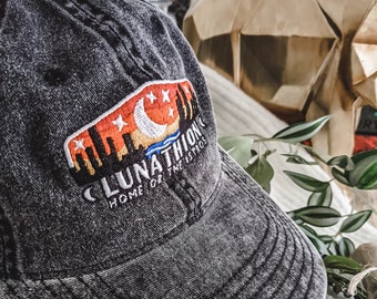 May include: A black denim baseball cap with a white embroidered patch that says "Lunathion Home of the Astros" with a crescent moon and stars in the background.