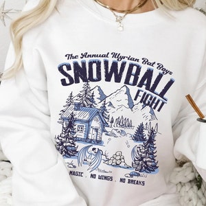 May include: White sweatshirt with a blue graphic print of a snowy mountain scene with a cabin and the text "The Annual Myrian Bat Boys Snowball Fight Magic. No Wings. No Breaks."