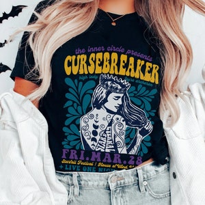 以下が含まれることがあります： 王冠とタトゥーをした女性が描かれたグラフィックプリントの黒いTシャツ。シャツのテキストは「the inner circle presents CURSEBREAKER high lady astro archer FRI.MAR.28 Starfall Festival | House of Wind + LIVE ONE NIGHT」です