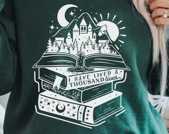 May include: A dark green sweatshirt with a white graphic design of a castle, trees, and a book with the text "I have lived a thousand lives".