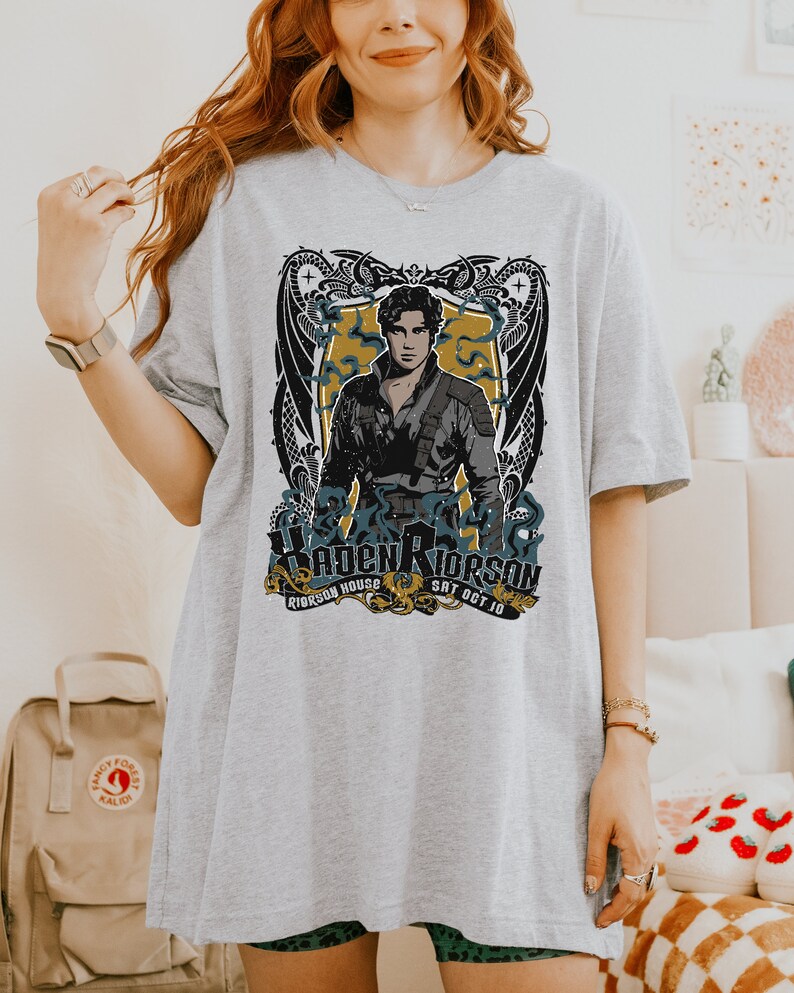 May include: Grey t-shirt featuring a graphic print of a man with a dragon design. The text on the shirt reads "Hayden Riderson, Riderson House, Sat Oct 10".