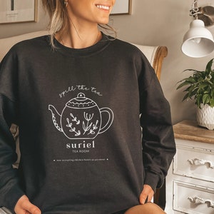 May include: Black sweatshirt with a white graphic of a teapot and the text "spill the tea suriel tea room now accepting chicken bones as payment".