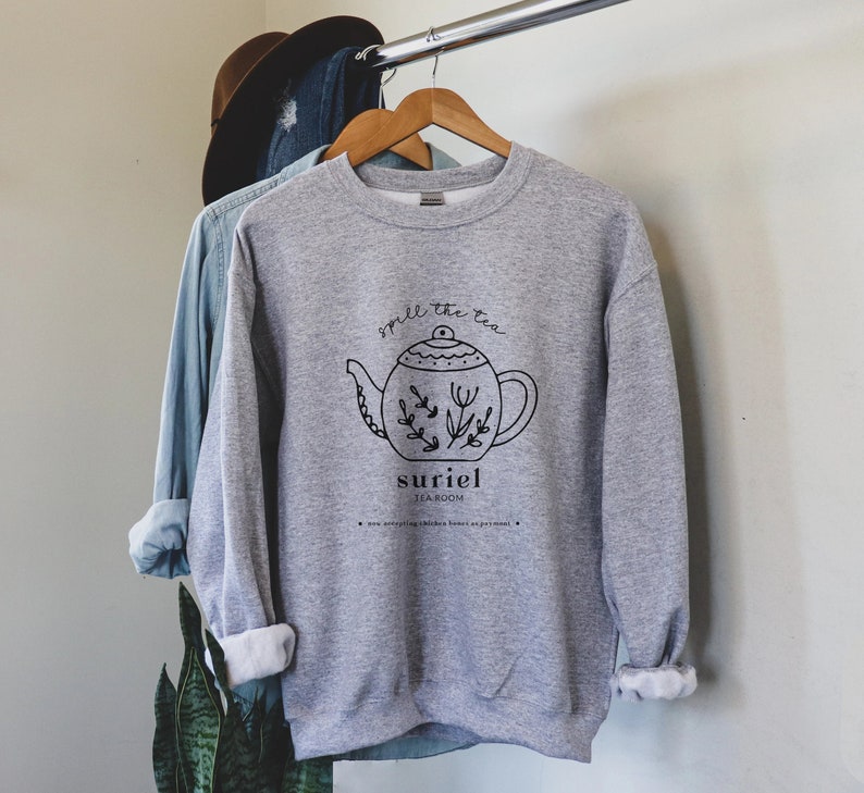 May include: Gray sweatshirt with a black and white illustration of a teapot with the text "Smell the tea" and "suriel tearoom" printed on the front.