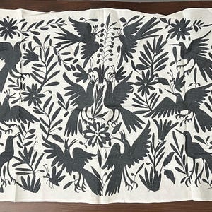 May include: A rectangular off-white textile featuring a dense, repeating pattern of dark gray embroidered birds, flowers, and leafy foliage. The design covers the entire surface with various avian figures in flight and perched positions.
