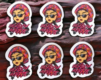 May include: Six white round stickers with a cartoon image of a woman wearing a pink and red floral headscarf and sunglasses. The text "DEADLY AUNTIE" is written in pink and black letters on each sticker.
